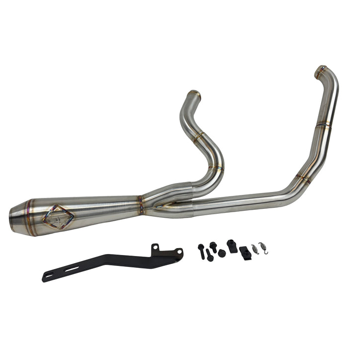 A custom SP Concepts Lane Splitter Exhaust for Harley-Davidson Dyna 1999-2005 lies on a workbench with welded joints; an American flag welding helmet is visible in the background. Stainless construction, ideal for exhaust builds.