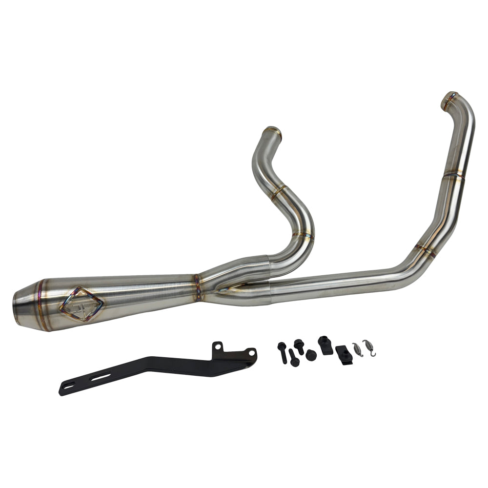 A custom SP Concepts Lane Splitter Exhaust for Harley-Davidson Dyna 1999-2005 lies on a workbench with welded joints; an American flag welding helmet is visible in the background. Stainless construction, ideal for exhaust builds.