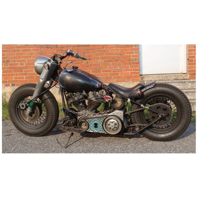 A motorcycle parked in front of a brick building, with a Monster Craftsman Bolt On Chain Tensioner - Skate Wheel (Powell Peralta) drive chain.