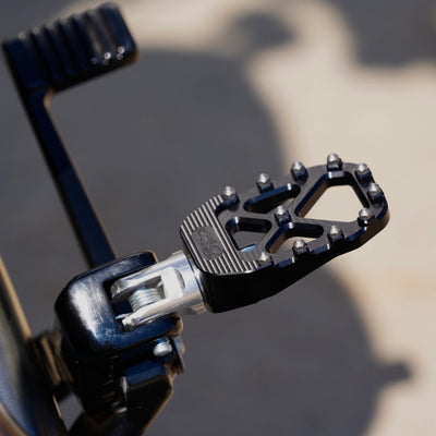 A close up of a TC Bros. Harley Davidson motorcycle foot pedal with Pro Series Black MX Rider Foot Pegs for high traction and stability.