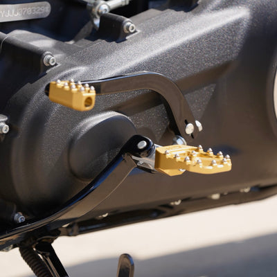 A close up of a TC Bros. Pro Series Gold MX Rider Foot Pegs for 2018-newer Harley Softail & Pan America motorcycle with precision machined gold brake pedals, ensuring high traction and stability.
