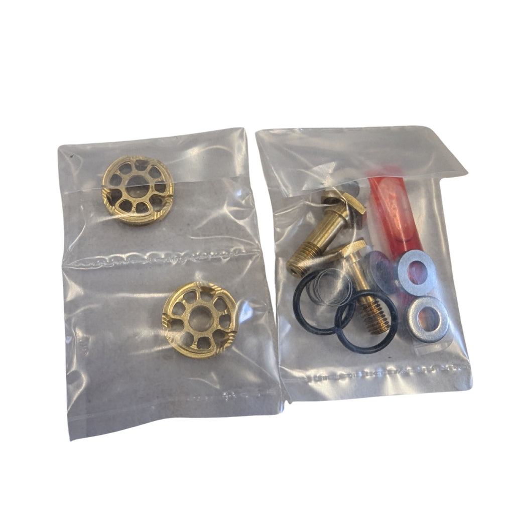 Two small sealed bags, one holding brass sprinkler heads and the other with screws, washers, O-rings, and a red piece—all on a white surface. It&