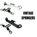 TC Bros. Headlight Mounting Bracket for Springer Front Ends (Vintage) includes chrome and black metal brackets plus hardware—ideal for springer headlight installation. Shown on white with "VINTAGE SPRINGERS" text. TC Bros. quality.