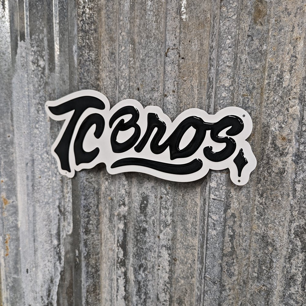 A TC Bros. Metal Shop Sign - Stamped Aluminum with the word "icons" in a cursive font, affixed to a textured gray stamped aluminum surface.
