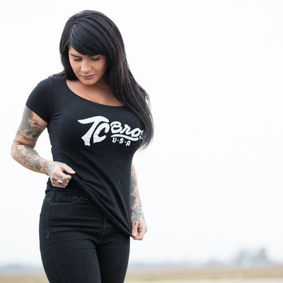 A woman wearing a black TC Bros. Women's Classic Tee with tattoos.