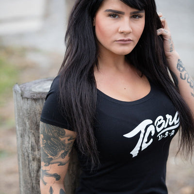 A woman wearing a black TC Bros. Women's Classic Tee with tattoos.
