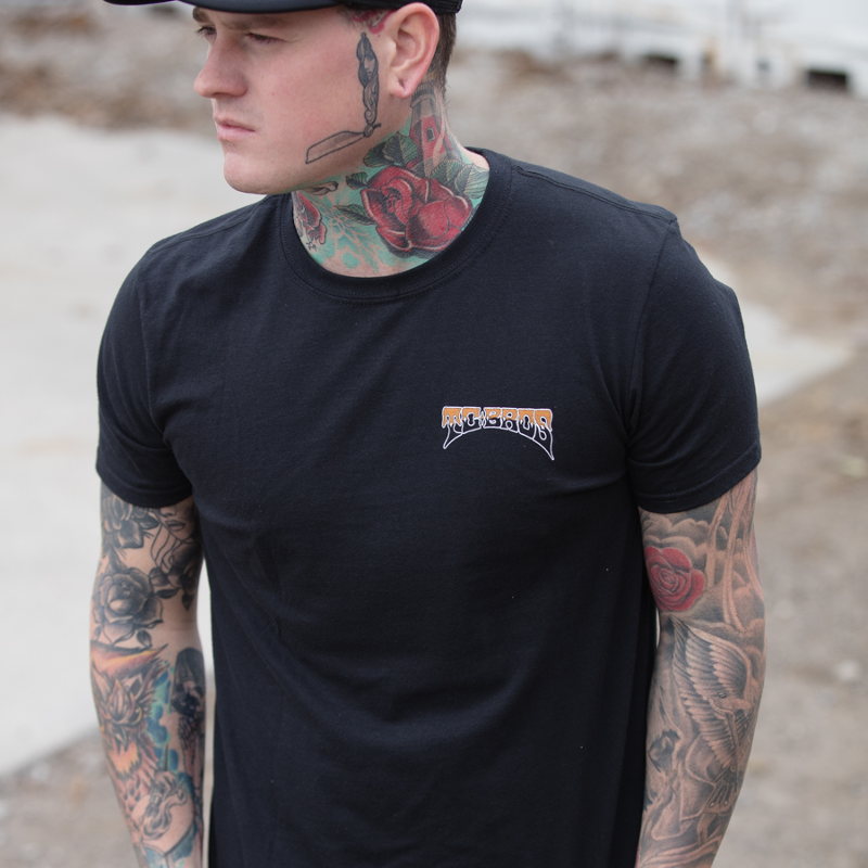 A man wearing a TC Bros. Drifter T-Shirt - Black with tattoos is seen.