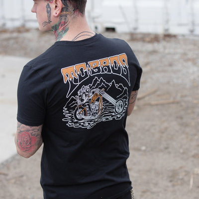 A man wearing a TC Bros. Drifter T-Shirt in Black with a motorcycle on it.