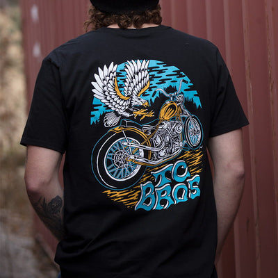 The back of a man wearing a TC Bros. Eagle T-Shirt - Black with the TC Bros. logo on it.