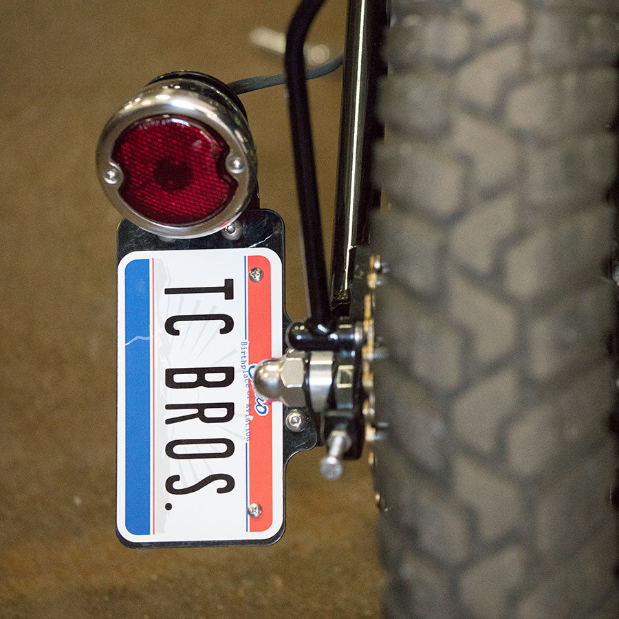 A motorcycle with a TC Bros. Black 33 Ford Replica Tail Light attached to it.
