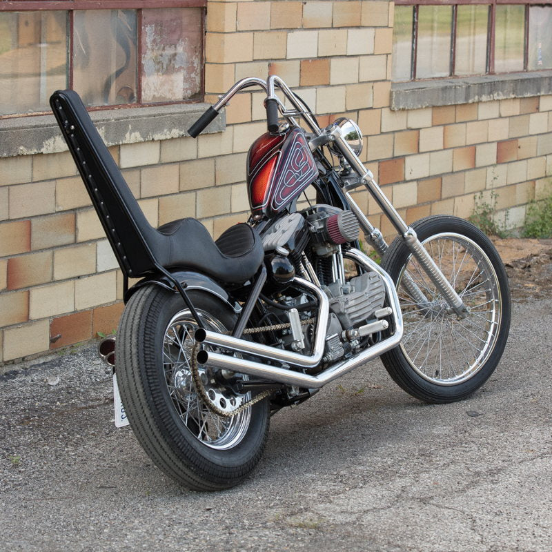 A Moto Iron® motorcycle parked in front of a brick building with a Chrome Front 40 Spoke Spool Hub Wheel 21 x 2.15 fits Harley (3/4" Bearings) chopper spool wheel.
