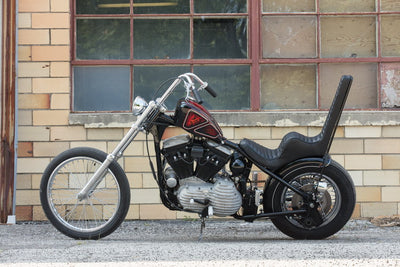 A motorcycle parked in front of a building with a TC Bros. Extended Fork Tube Kit +6" 39mm for Sportster/ Dyna Narrow Glide with Hard Chrome Finish.
