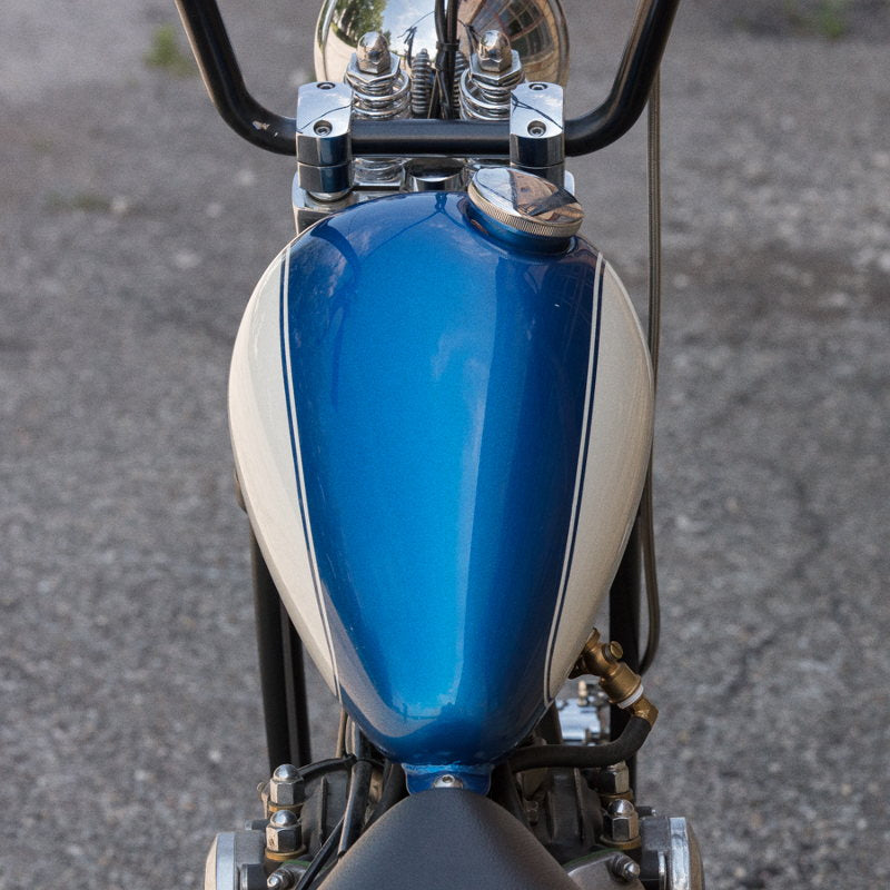 A blue and white custom chopper motorcycle with a 2.2 Gal. Axed Tank from Moto Iron® is parked in a parking lot.