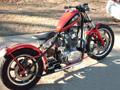 A red and black custom Moto Iron® chopper parked on the side of the road.