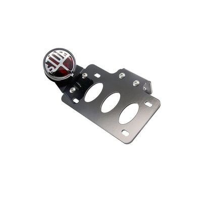 A versatile TC Bros. "Stop" Bobber Side Mount Tail Light/License Plate Bracket with a black plate and a red and black logo on it.