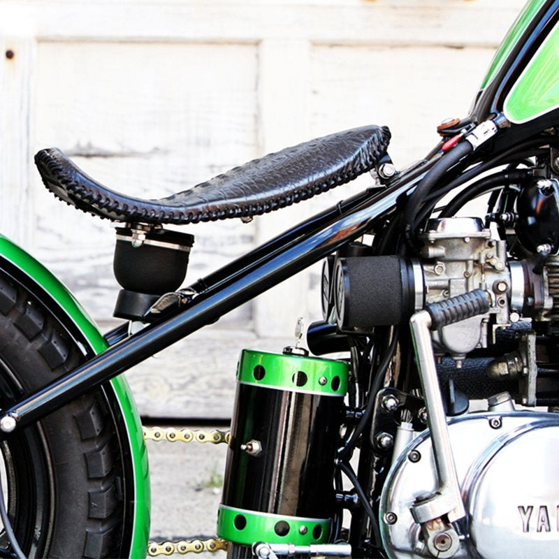 A motorcycle parked in front of a garage, showcasing its power and performance with the UNI Filter Clamp-on High Flow Air Filter Kit (pair)(2.125"-2.25") carburetor.