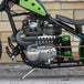 A TC Bros. green motorcycle parked in front of a brick wall.