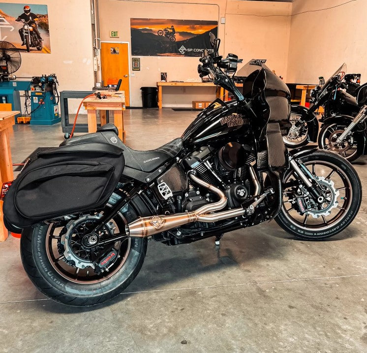 An SP Concepts Big Bore Exhaust M8 Softail ST & Sport Glide 2018-Present (stainless) motorcycle is parked in a garage.