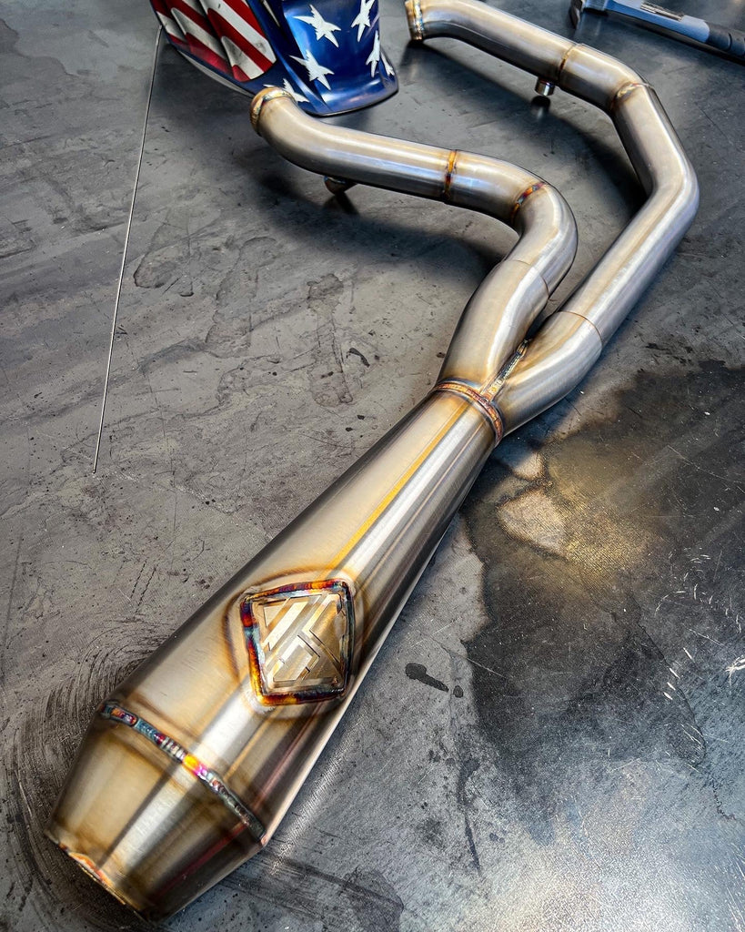 A SP Concepts Lane Splitter Exhaust 06-17 Dyna (stainless) with a SP Concepts flag on it.