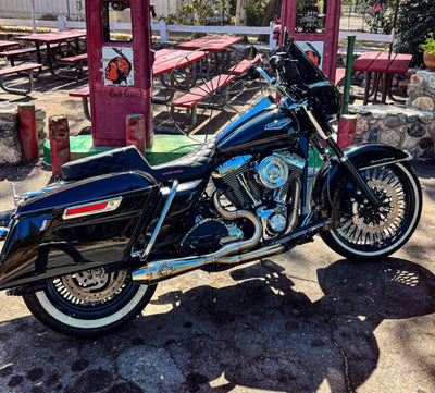 A black motorcycle parked in front of a restaurant with the SP Concepts Big Bore Exhaust Twin Cam Touring 96-16 (stainless) installed.