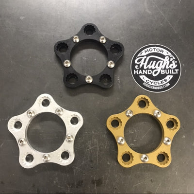 Four types of HHB Harley Davidson Sprocket Lock System - Gold wheel spacers, including XL Big Twin and Buell motorcycles, with a gold anodized aluminum finish, displayed on a table.