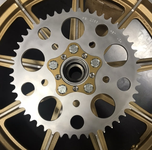 A close up of a HHB Harley Davidson Sprocket Lock System - Gold sprocket wheel by Hughs Handbuilt.