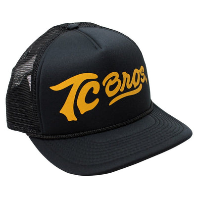 A black and yellow TC Bros. Script Trucker Hat with the word tcens on it.