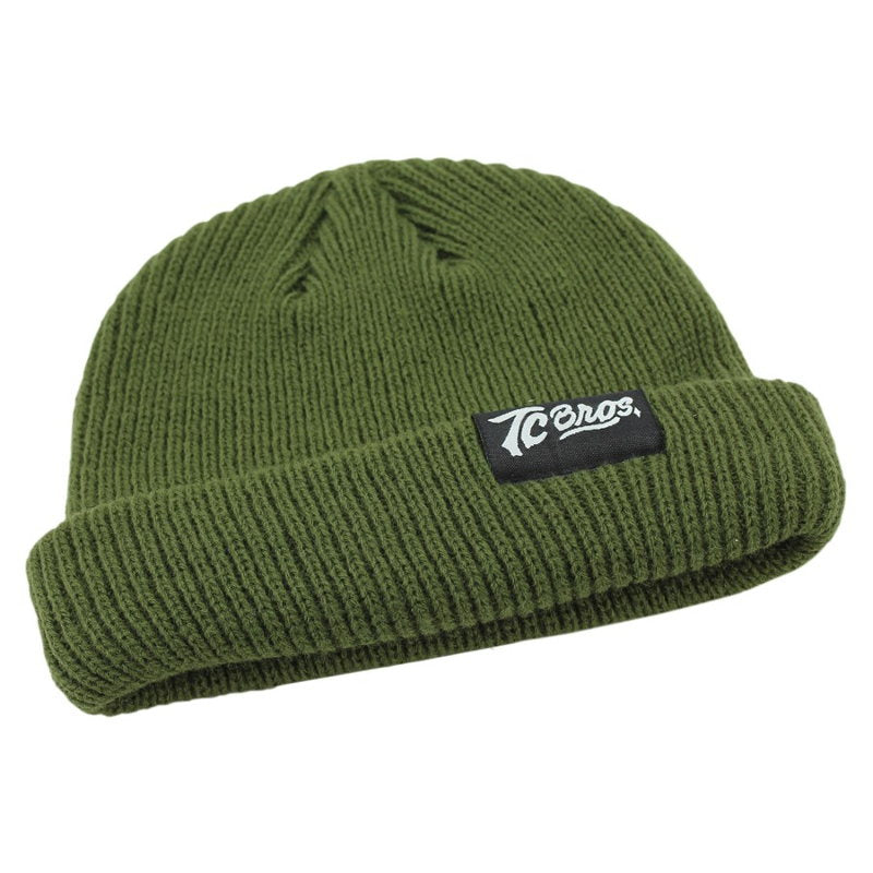 A TC Bros. Watchman Beanie - Surplus with a ribbed knit construction and logo on it.