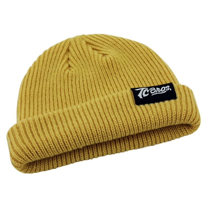 A soft acrylic yellow beanie with a black patch, the TC Bros. Watchman Beanie - Nugget, is a stylish accessory offered by TC Bros.