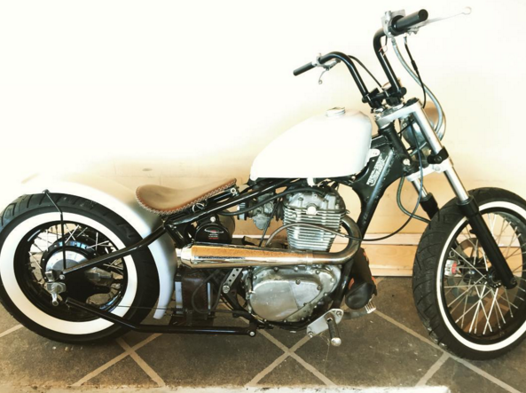 A white TC Bros. motorcycle with American steel tubing parked on a tile floor.