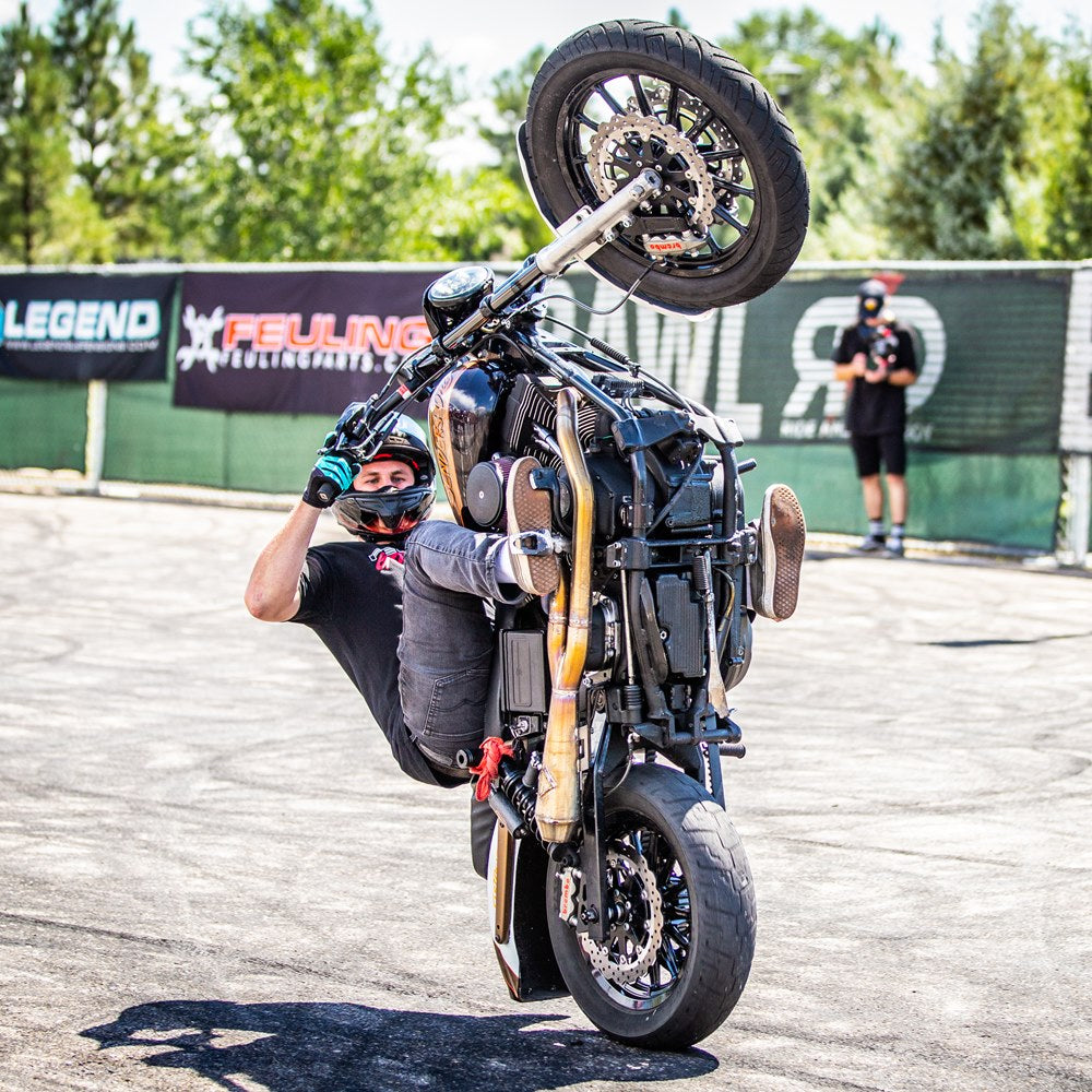 A man performing an impressive trick on a TC Bros. 11.8in Profile™ Front Floating Brake Rotor for 2006-23 Harley Models motorcycle.