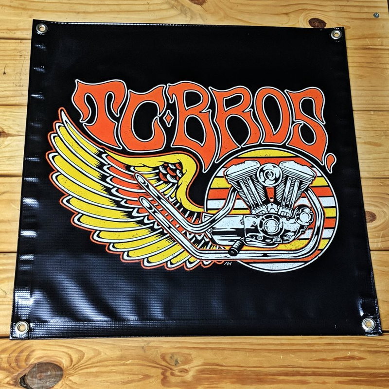 A black vinyl TC Bros. Wing Banner 2ft x 2ft with hemmed edges and metal grommets, featuring an image of a Harley-Davidson Harley-Davidson.