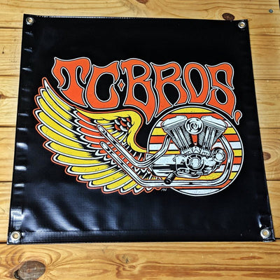 A black vinyl TC Bros. Wing Banner 2ft x 2ft with hemmed edges and metal grommets, featuring an image of a Harley-Davidson Harley-Davidson.