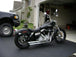 A black Burly Slammer 10.5" Shocks for Harley Davidson Dyna FXD 1991-2015 - Black motorcycle parked in front of a garage.