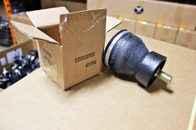 A box containing a rubber ball and a TC Bros. Choppers Air Spring.