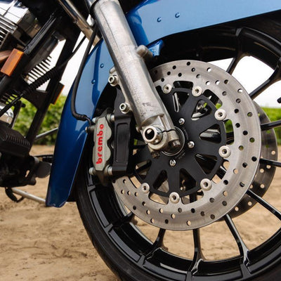 A close up of a blue motorcycle with a TC Bros. Black Front Radial Brake Bracket 2000-17 Harley Stock Rotor that showcases its stopping power.