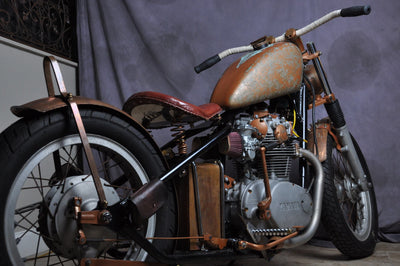 An Old School motorcycle with a brown seat and Mid-USA Black Handlebar Grips.