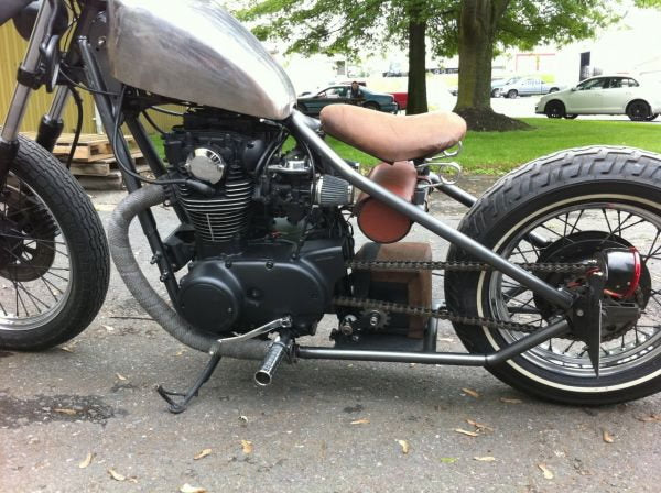 A silver motorcycle equipped with a Monster Craftsman 1.125 CLAMP ON CHAIN TENSIONER 530 SPROCKET parked in a parking lot.