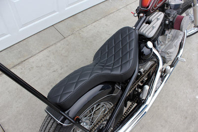 A motorcycle with a TC Bros. Hardtail Rigid Cobra Seat Black Diamond parked in front of a garage.
