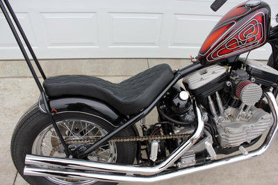 A motorcycle with TC Bros. Hardtail Rigid Cobra Seat Black Diamond seats parked in front of a garage.