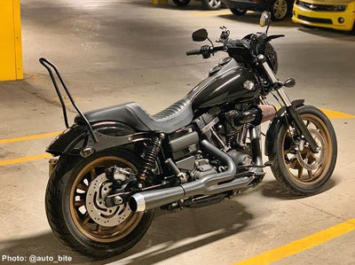A black TC Bros. Dyna 06-17 Kickback Sissy Bar Chrome motorcycle is parked in a parking lot.