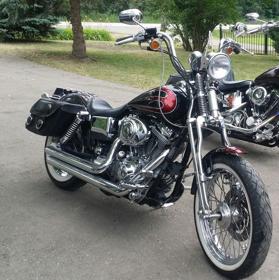 Two motorcycles, a Dyna 1992-2017 & Sportster 2004-Newer and a Moto Iron® Wishbone Springer Front End for Harley Davidson Dyna 91-17 & Sportster 04-Up (Stock Length, Chrome), parked on the side of the road.