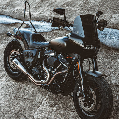 A black TC Bros. motorcycle parked on a concrete surface, with gear.
