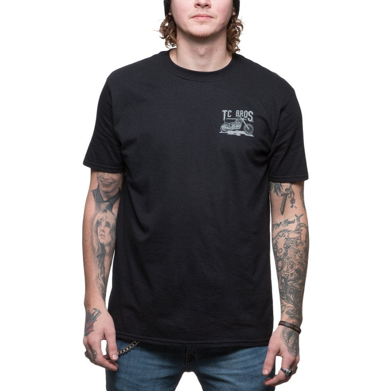 A man wearing a TC Bros. Sketchy T-Shirt - Black with tattoos and a sketchy design.