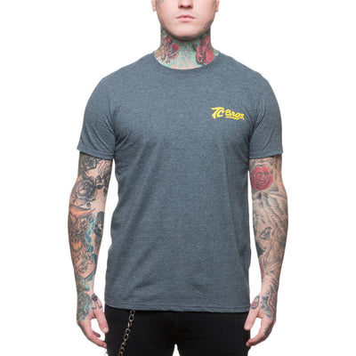 A man wearing a grey t-shirt, adorned with tattoos, dons the TC Bros. Shield T-Shirt in Charcoal Heather.