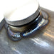 A close up of a TC Bros 5 inch Round Chopper Oil Tank Flat Ends Universal Fit flask with a metal lid, made in the USA.