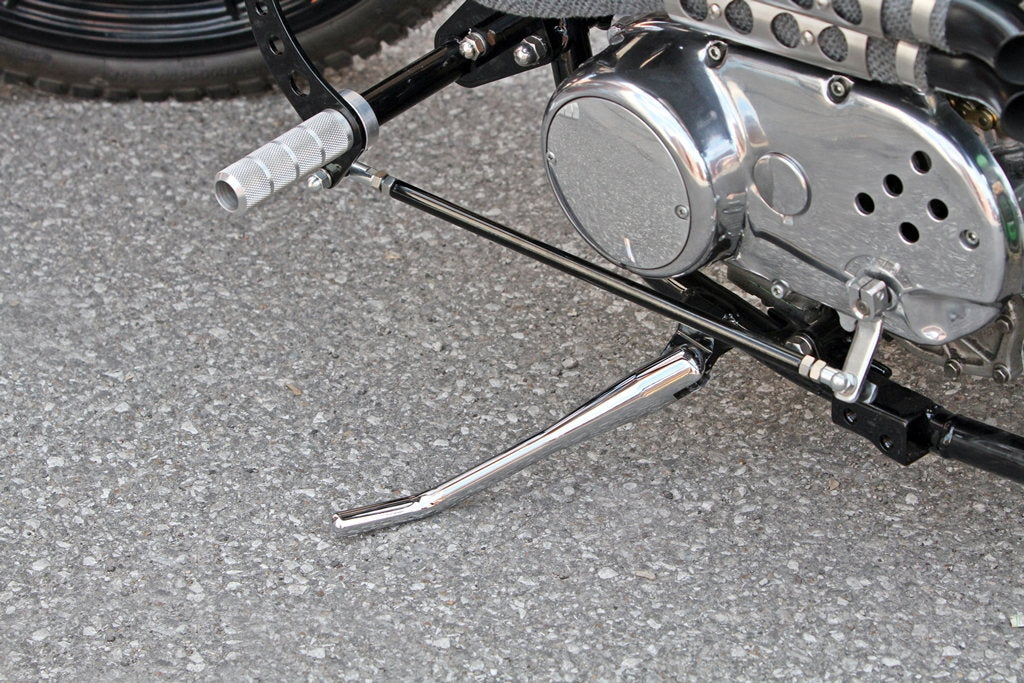 A motorcycle with a chain on the ground and a TC Bros. Chrome Weld On Kick Stand for 1" Frame Tubing kickstand.