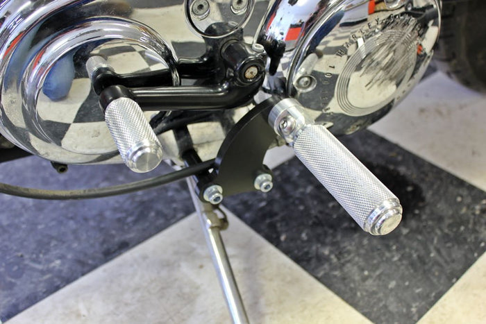 The TC Bros. Mid Controls Kit for 1991-2003 Harley-Davidson Sportster features metal foot pegs and a gear shift lever, perfect for upgrading your bike. Components are arranged on a white background.
