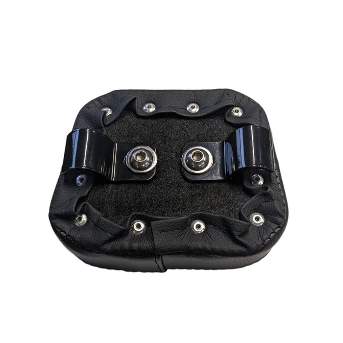 A TC Bros. black leather pad with two metal clamp buttons on it.