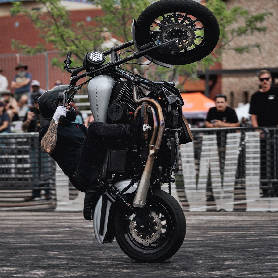 A man performing a gravity-defying handstand on a motorcycle equipped with TC Bros. 11.5in Profile™ Rear Floating Brake Rotors and Harley Davidson wheels.